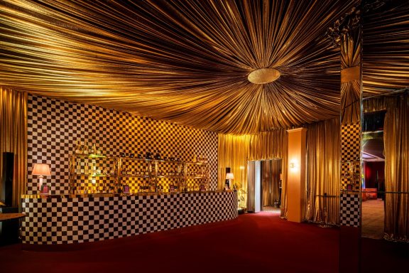 Gold lame drapes installed for the BRITs after party at Claridge’s in London, creating a luxury event backdrop
